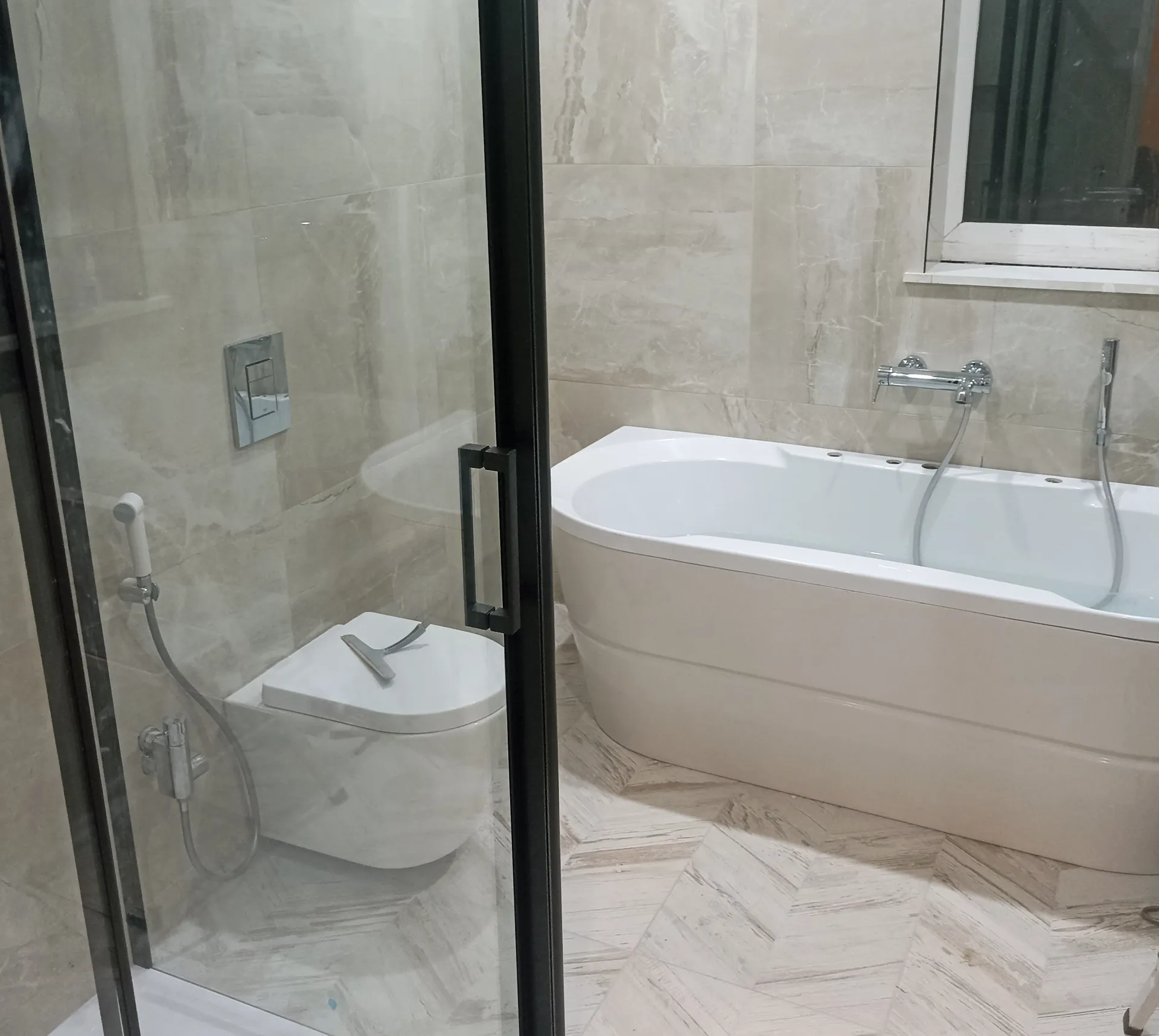 Bath, tiled walls and glazed shower enclosure during final fitting.