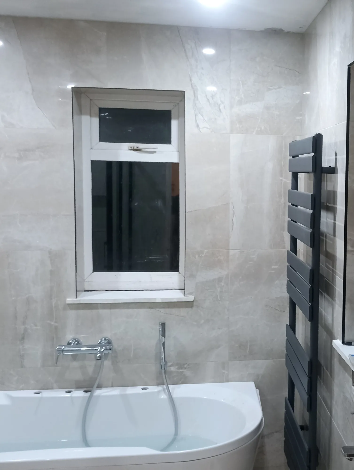 Wall tiling, bath and heated towel rail during bathroom fit-out.