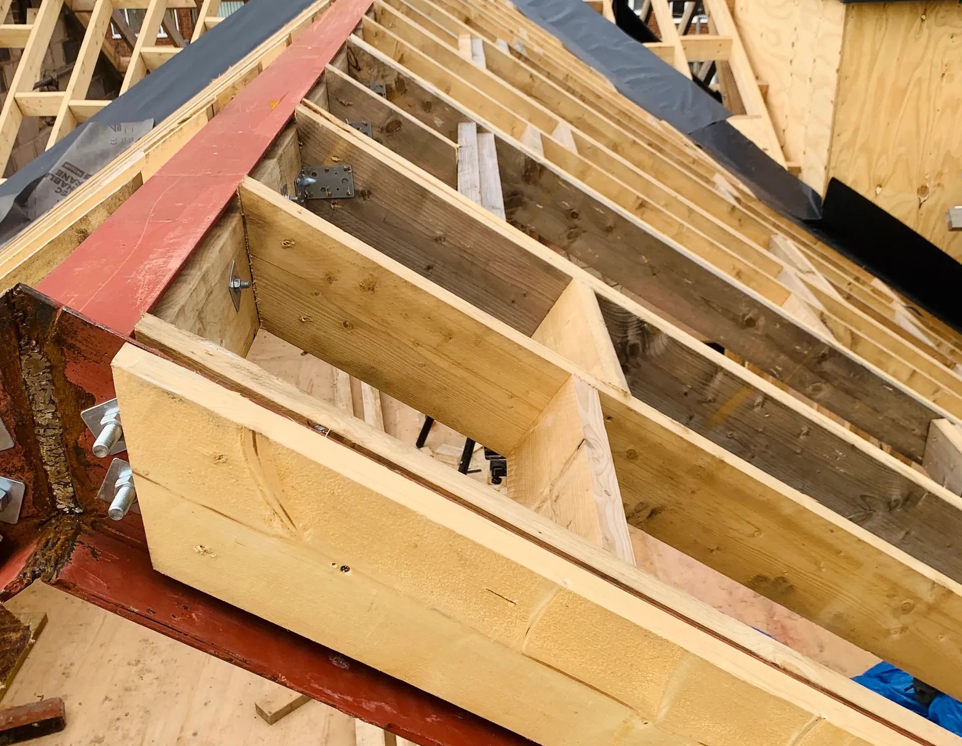 Rafters, ridge steel and framing junctions before the roof is enclosed.