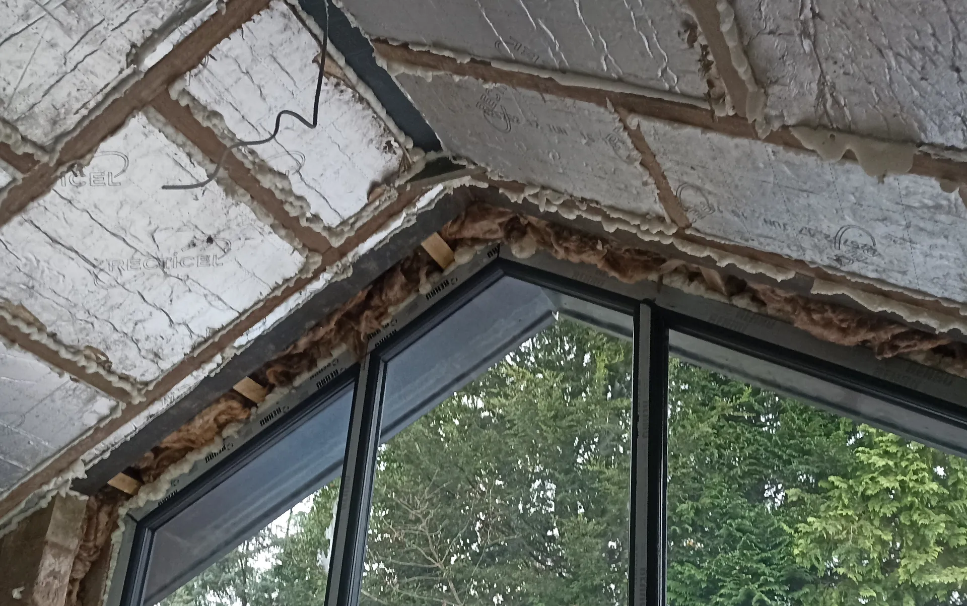 Foil-faced insulation and roof framing above the glazed extension.