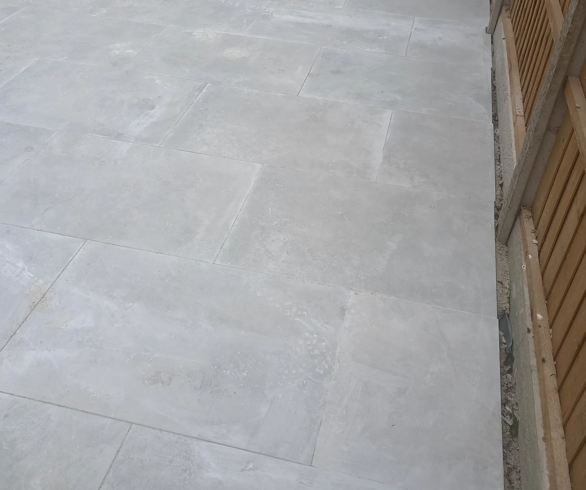 Large-format paving laid alongside timber fencing.