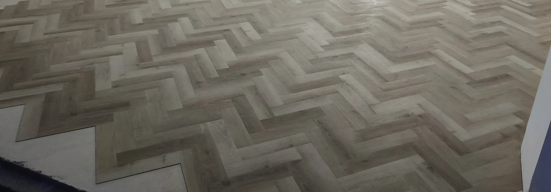Herringbone-pattern flooring during installation before the room is completed.