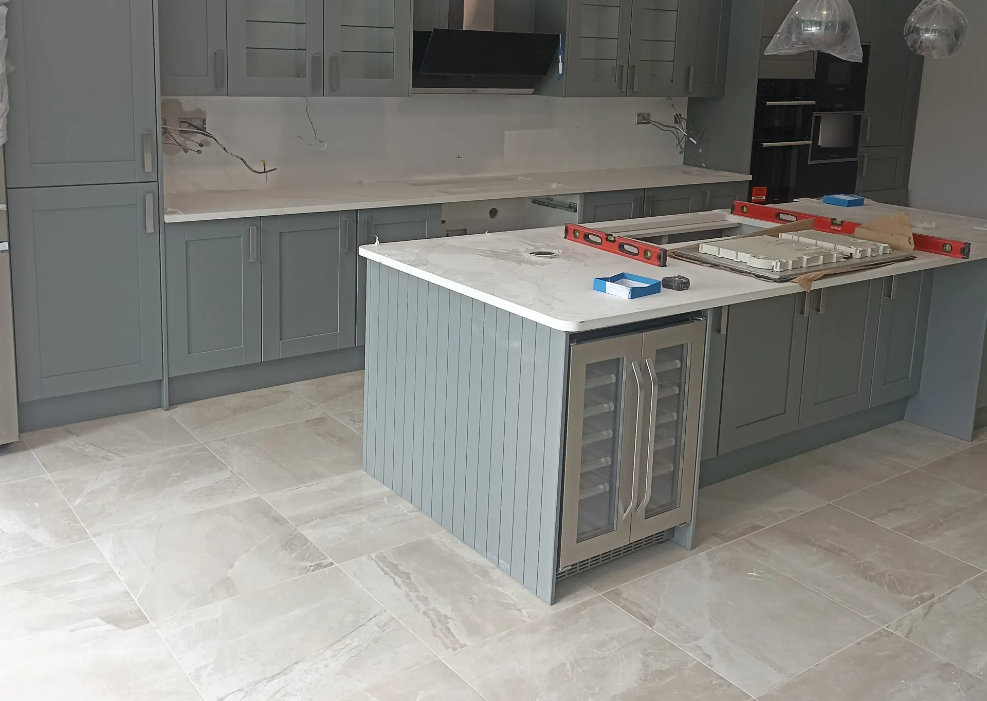Kitchen cabinetry, island and floor tiling during fitting, before final electrical and appliance completion.