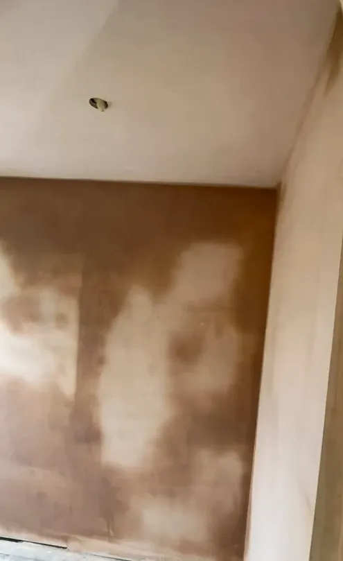 Fresh skim plaster across the wall and ceiling, drying before decoration.