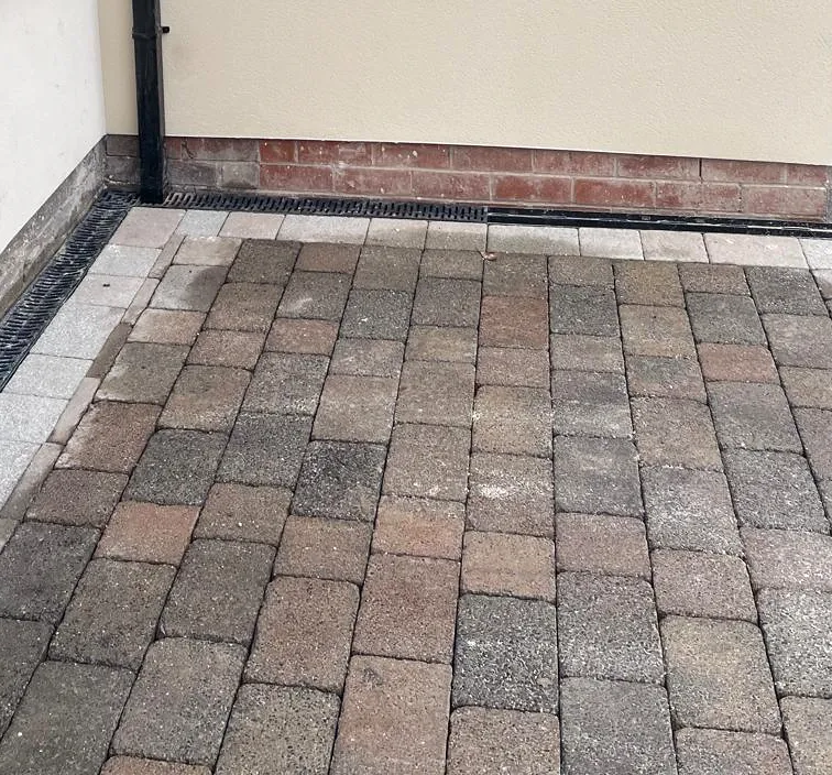 Rendered wall, paving and channel drainage at an external corner.