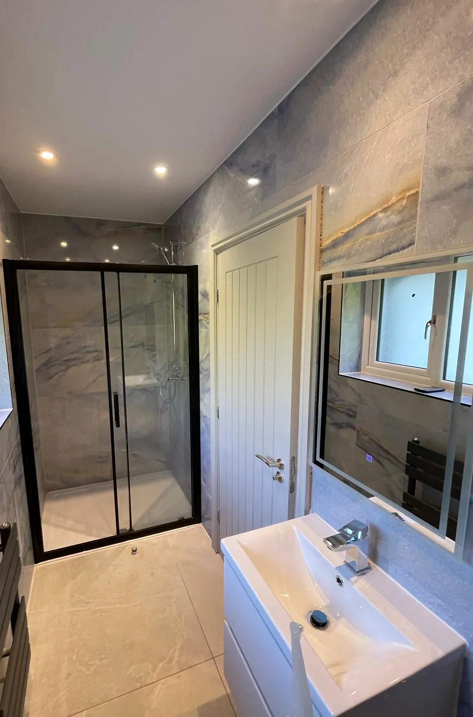 Shower enclosure, vanity and tiled finishes in a compact shower room.