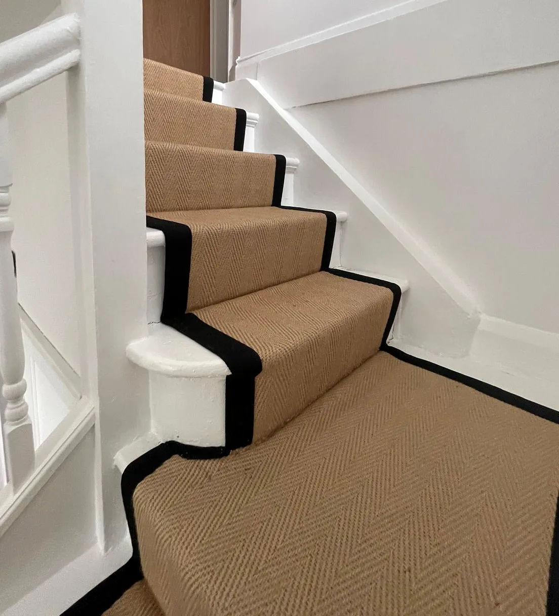 Fitted stair carpet beside painted string, skirting and wall panelling.