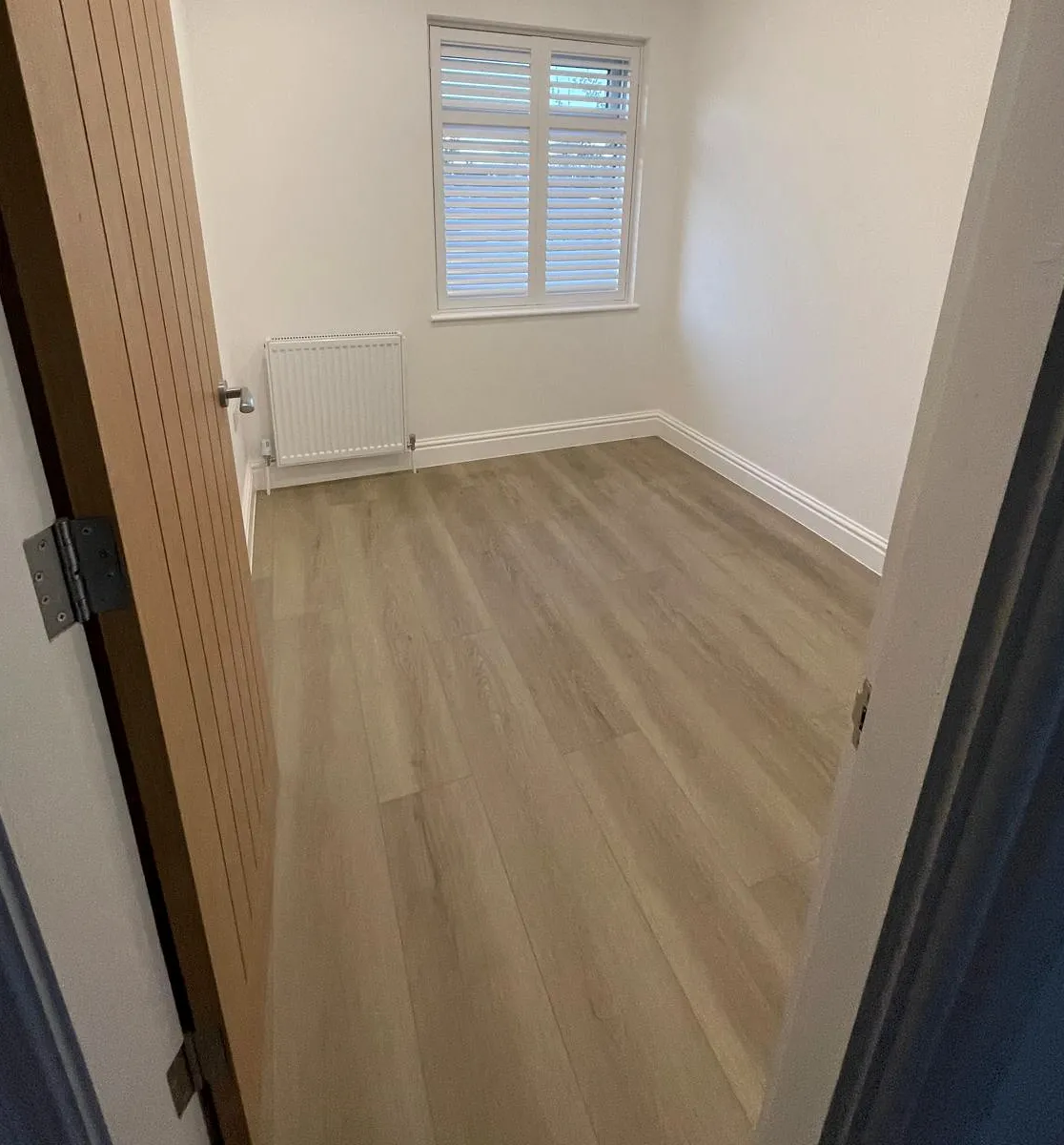 Wood-effect plank flooring with painted walls and skirting.